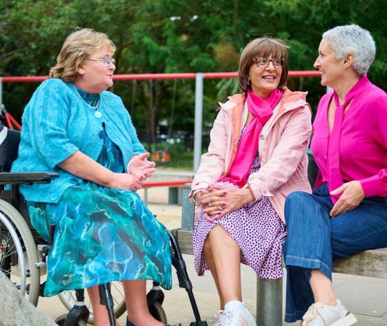 Three women sitting together outdoors talking to each other