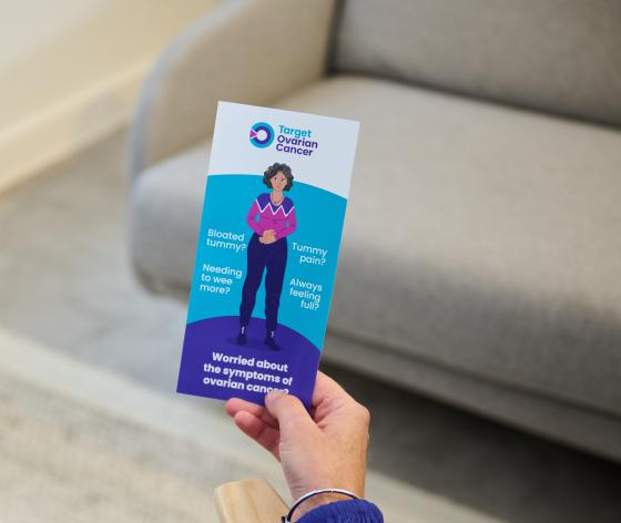 Someone holding out a symptoms awareness information leaflet from Target Ovarian Cancer