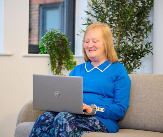 Woman sitting on sofa looking at laptop on her lap