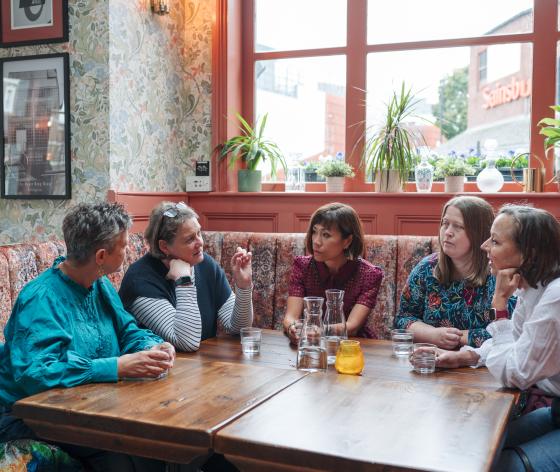 Group of women sat around a table talking
