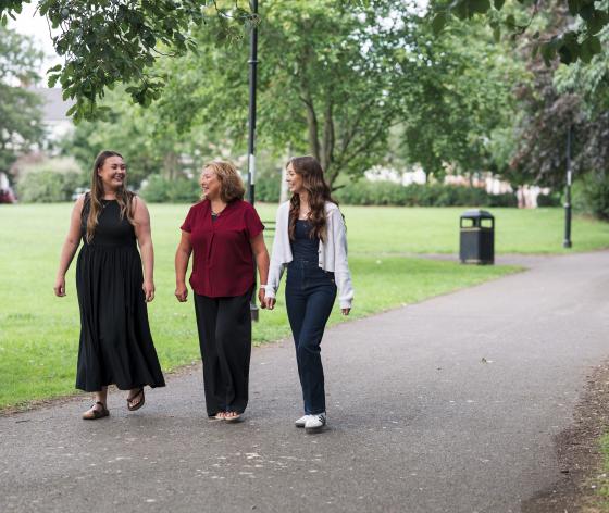 Three women walking together in the park chatting and smiling