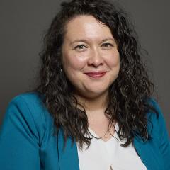 A headshot image of Victoria Collins MP wearing a white blouse and teal coloured blazer