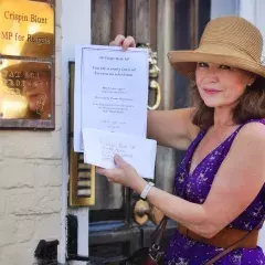 Woman holding up an invitation whilst standing outside the door of an office