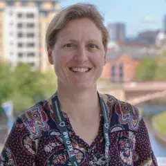 A headshot image of Dr Barber standing outside in the sun smiling