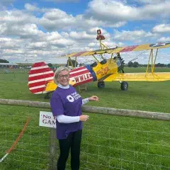 A female supporter smiling in front of a wing walking plane
