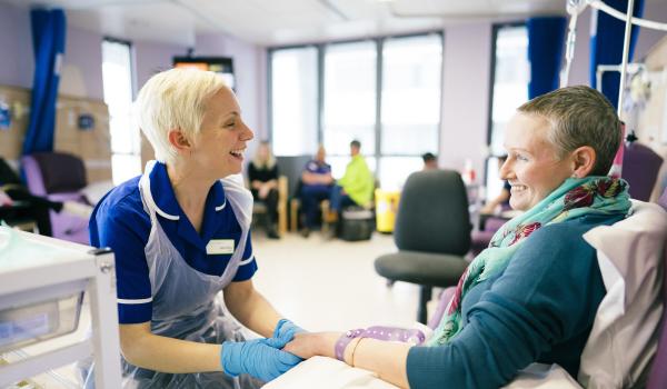 A nurse talking and smiling with a woman during chemotherapy