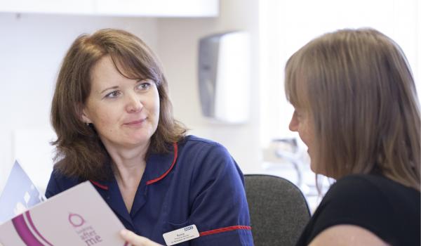 A nurse talking through a Target Ovarian Cancer leaflet with a woman