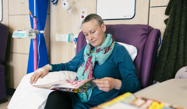 A woman reading a magazine while having chemotherapy