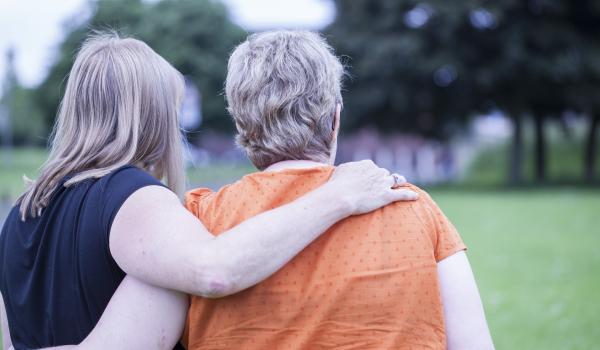 A woman with her arm around the back of another woman 