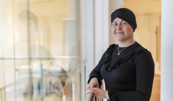 A woman with ovarian cancer smiling wearing a black head scarf and a black top