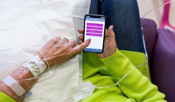 Close up of a woman scrolling through Target Ovarian Cancer's website on her phone during chemotherapy