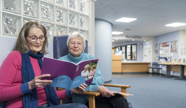 Two women reading a Target Ovarian Cancer guide in a hospital