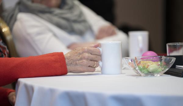 Close up of a cup of tea with two women talking in the background at a Target Ovarian Cancer support event