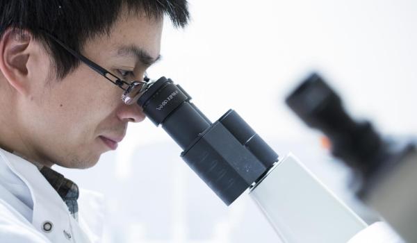 An ovarian cancer researching looking into a microscope