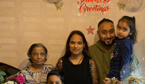 Lena with her mum Savita at a 40th birthday party surrounded by their family, a cake, flowers and some cards