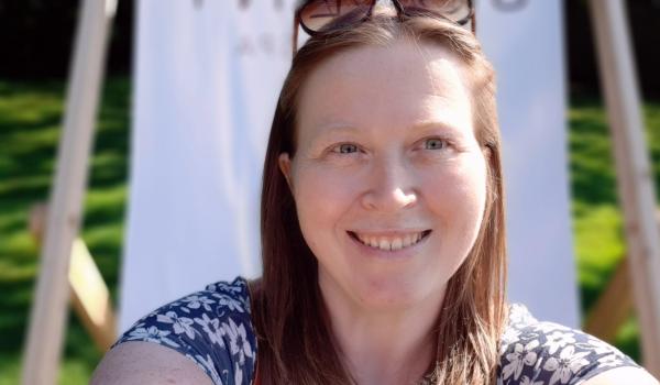 Claire smiling with a deckchair behind her