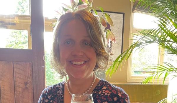 Alex wearing a dress and holding a glass of wine