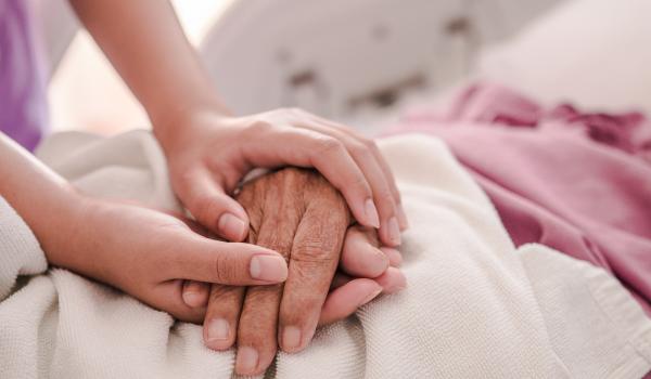 Two people holding hands on a hospital bed