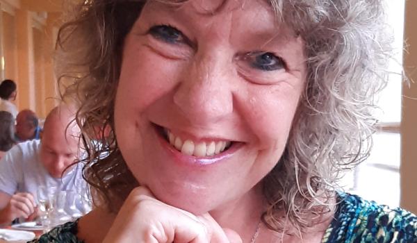 Gill sitting and smiling towards the camera with her chin resting on her hand