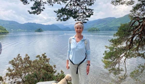 Lesley standing by a lake out walking with her dog