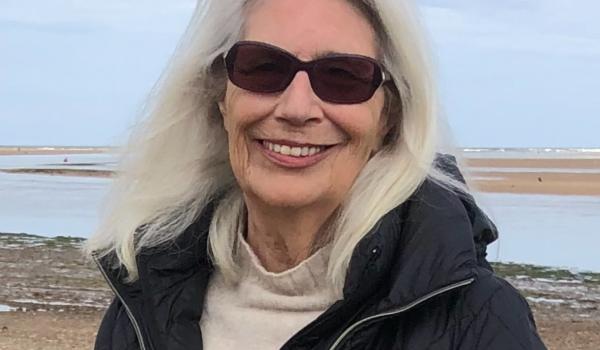 Mo at the beach wearing sunglasses smiling for a photo