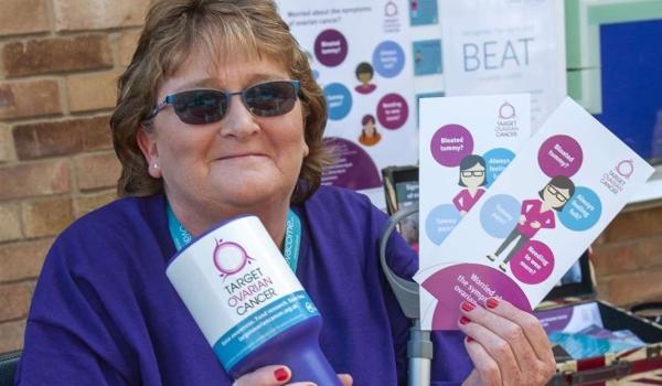 Diane out fundraising in her local community, holding a collection tin and Target Ovarian Cancer posters and leaflets
