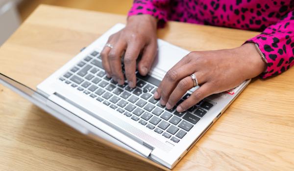 A person's hands typing on a laptop