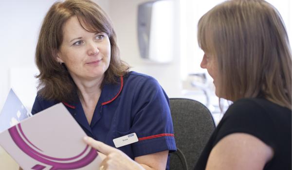 A nurse talking through a Target Ovarian Cancer leaflet with a woman