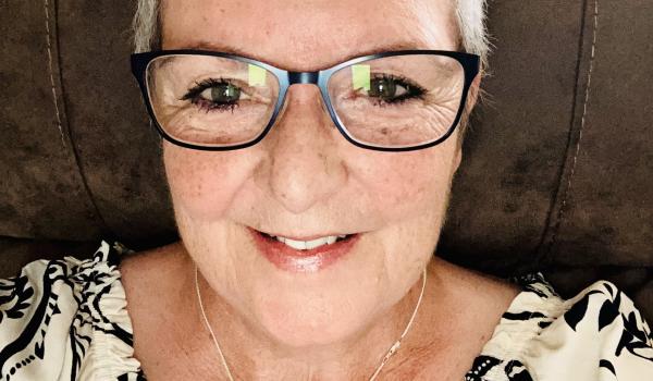 A selfie of Dot with short blonde hair wearing glasses and smiling