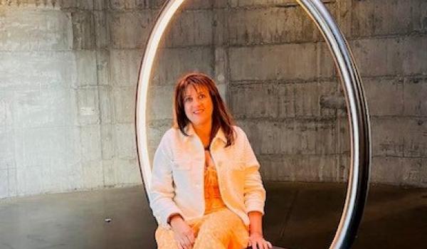 Reeta smiling sat in a hoop chair