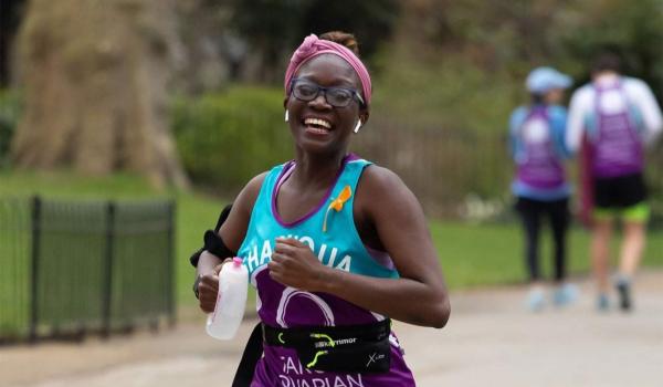 Shaniqua running in a London park taking on Run for Mum wearing her Target Ovarian Cancer running vest