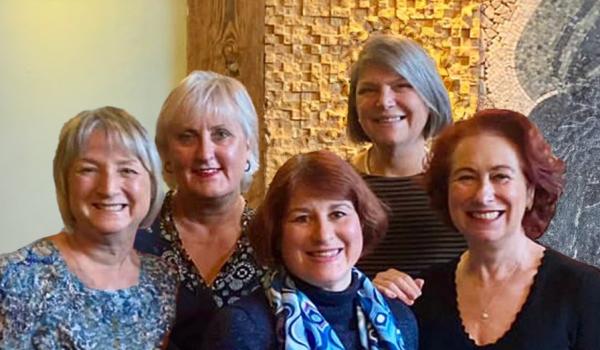 Five women all standing next to each other smiling