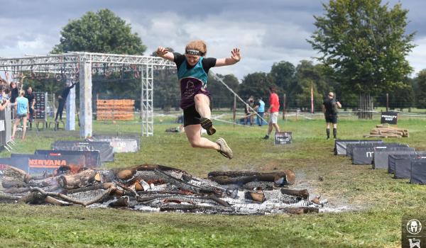 Georgia jumping over a ditch taking on the spartan challenge in her target ovarian cancer tshirt