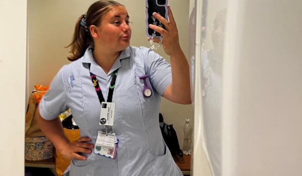 Rosie taking a photo in the mirror wearing her student nurse uniform