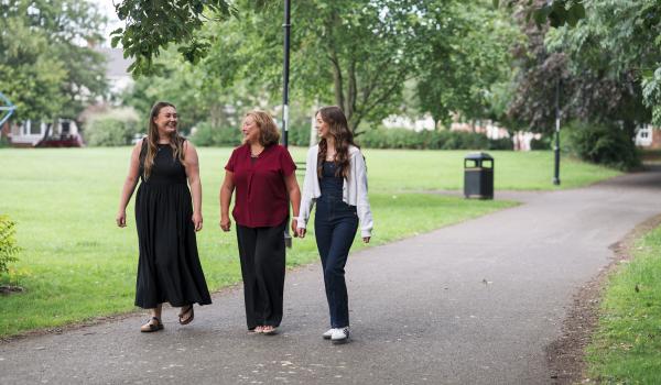 Three women walking together in the park chatting and smiling