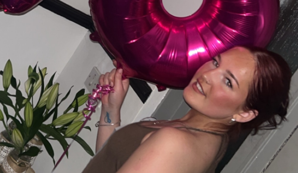 A photo of Taegan on her 18th birthday holding pink 1 and 8 balloons