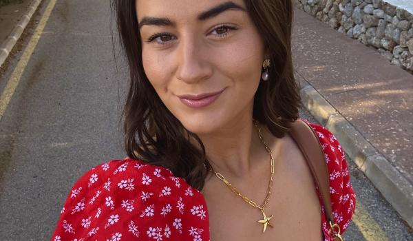 A selfie of Lucy wearing a red dress with short brown hair smiling