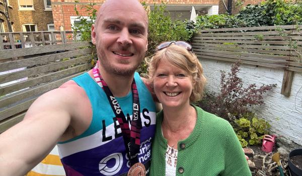 A selfie of Lewis and his mum Janet both smiling. Lewis is wearing his Target Ovarian Cancer running vest and his London Marathon medal