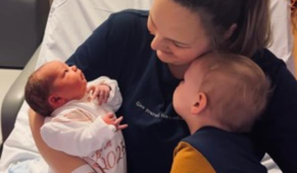 Grace holding her child and newborn baby.