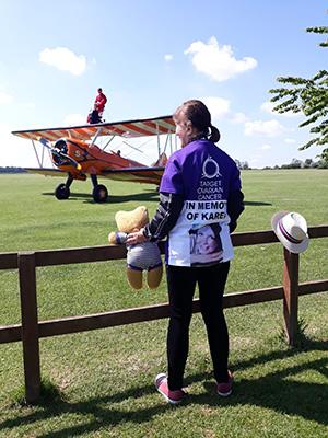 Elaine looking at a biplane holding her daughter's teddy bear