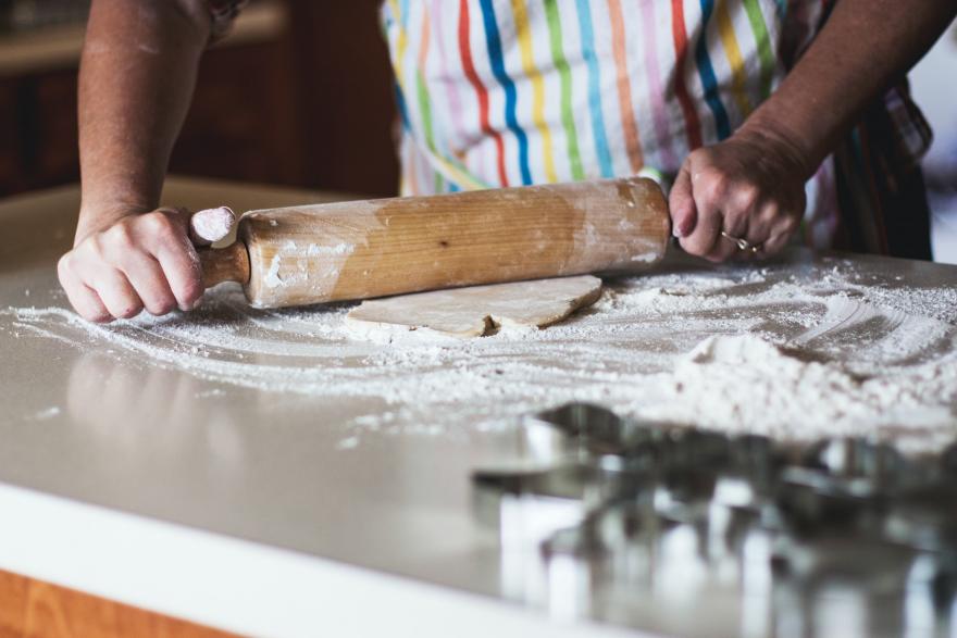 A baker rolling out dough on a floured surface