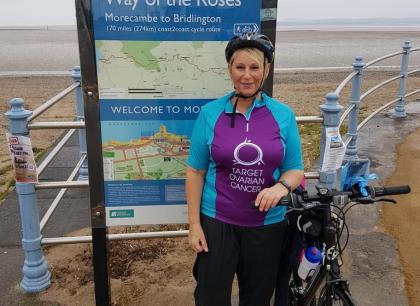 A target ovarian cancer fundraiser smiling next to her bike at the seafront