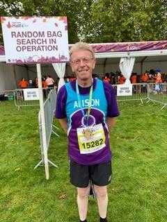 Colin standing in his Target Ovarian Cancer running vest with a medal around his neck having just complete a half marathon