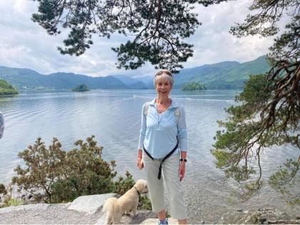 Lesley standing by a lake out walking with her dog