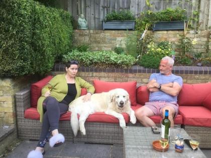 Lorraine sitting on a sofa outside next to a dog enjoying time with friends