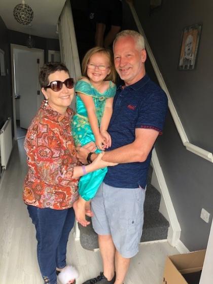 Lorraine and her husband holding their granddaughter all smiling for a photo