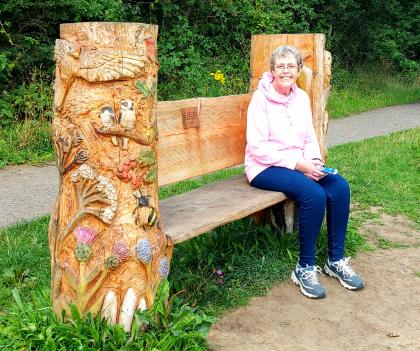 Helen sat on a large wooden bench in the park