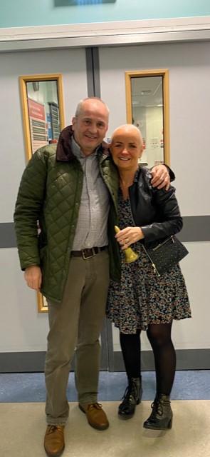 Declan and Pauline with his arm around her in hospital smiling standing at the doors about to go home