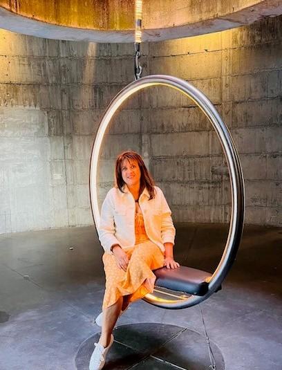 Reeta smiling sat in a hoop chair