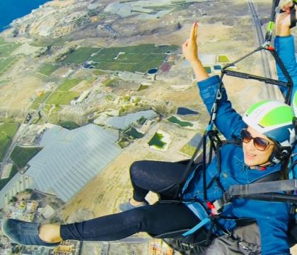 Reeta paragliding smiling with views of the ground below